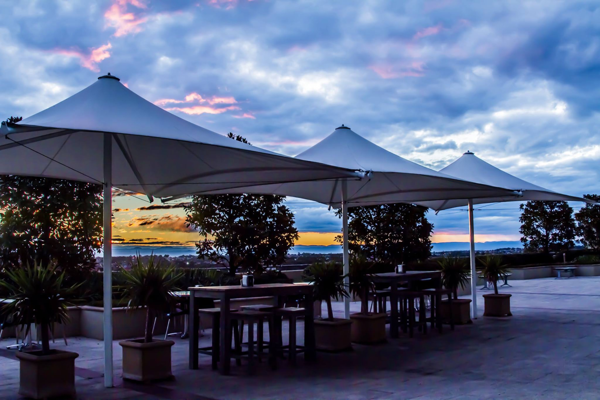 Bella Vista terrace at sunset with market umbrellas and warm spring skies