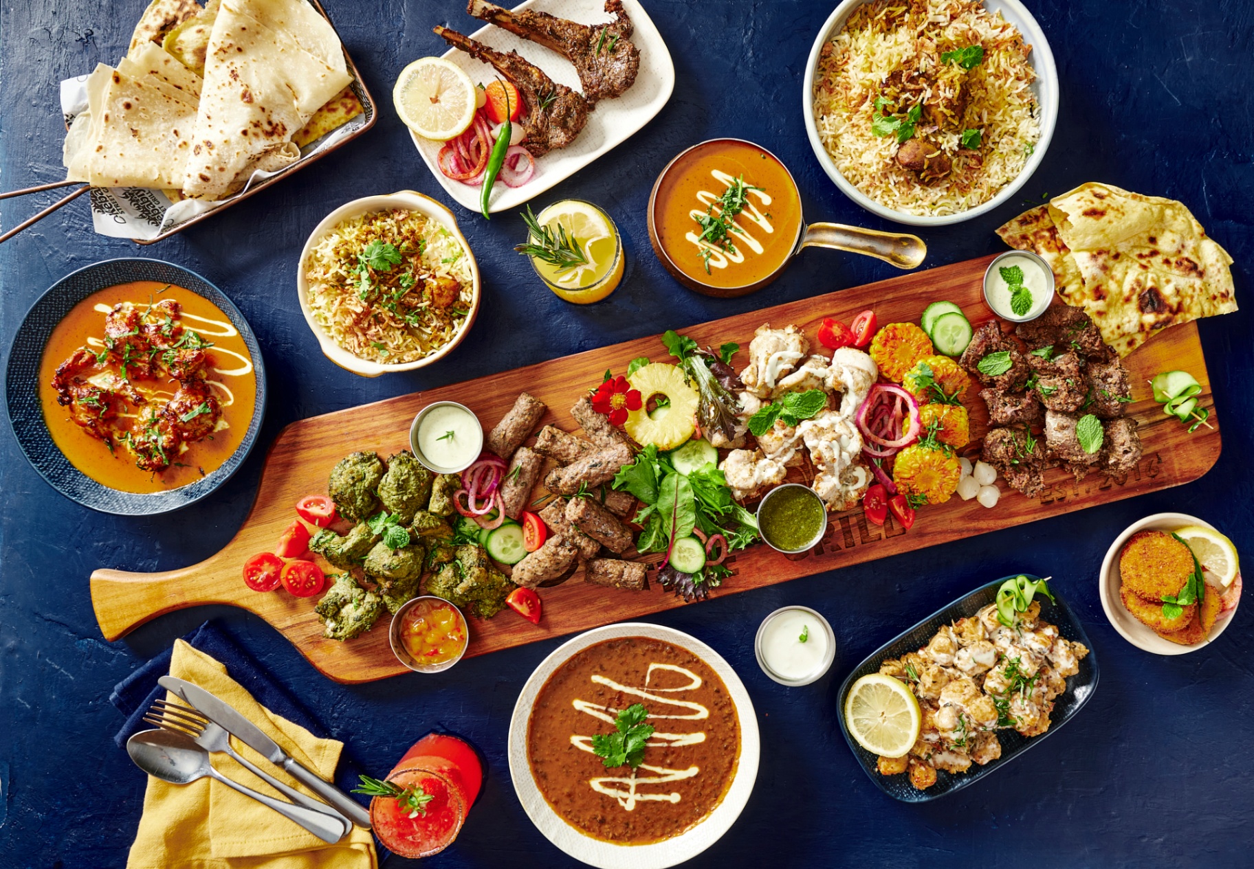 Kebabiya feast — mixed grill platter with kebabs, biryani, curries, naan and chutneys on a deep blue table